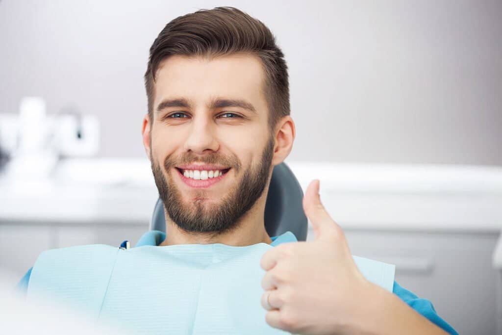Patient giving thumbs up after dental cleaning